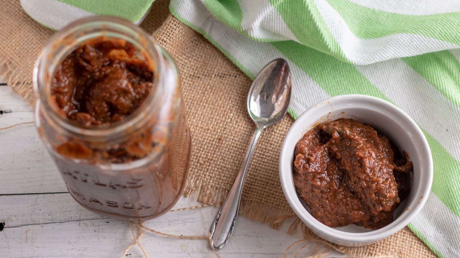 Jar and bowl of chipotle in adobo with silver spoon.