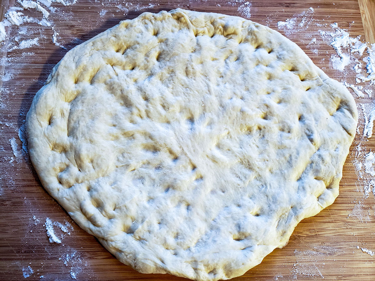 Shape and roll the dough into a round pizza.