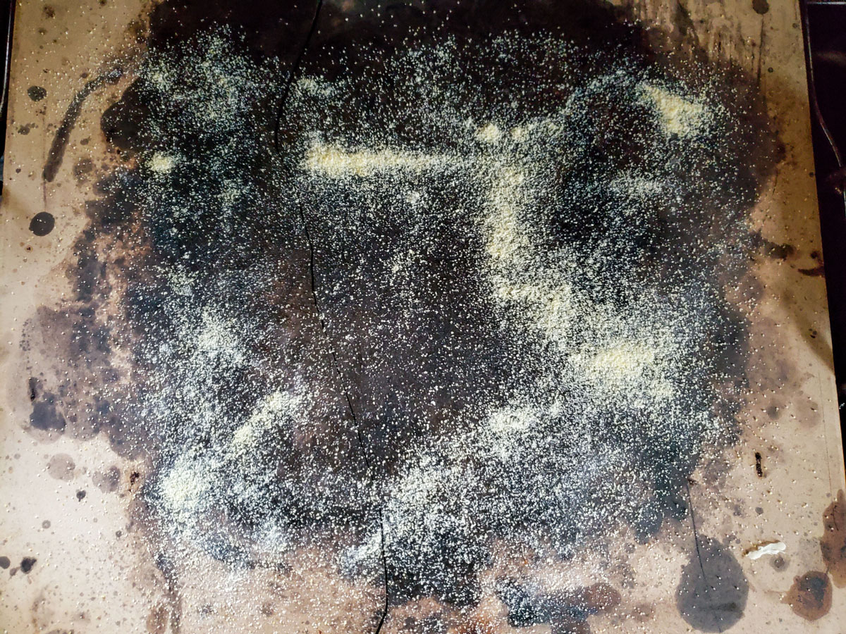 Cornmeal sprinkled on a pizza stone.