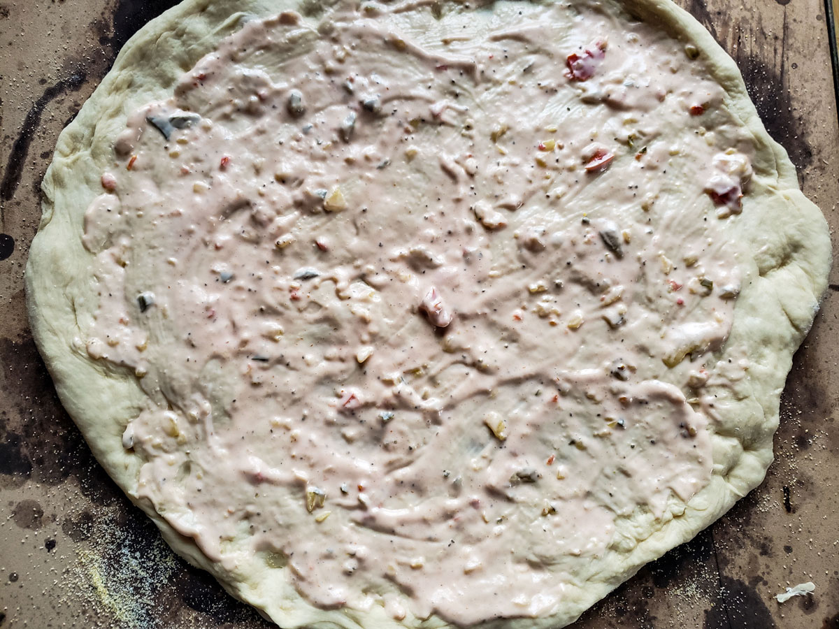 Dough placed on the stone and topped with sauce.