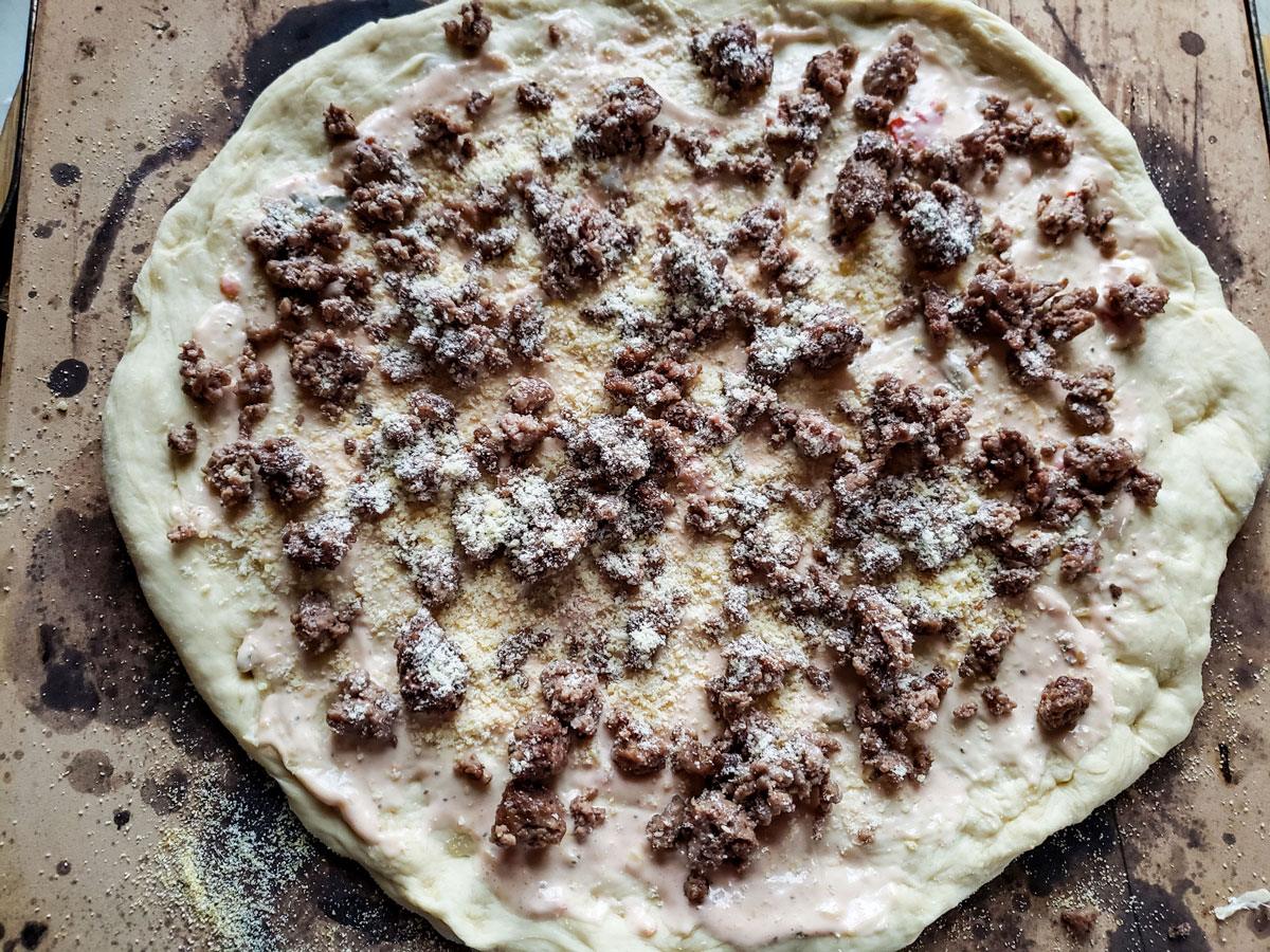 Dough sprinkled with the meat and some cheese.