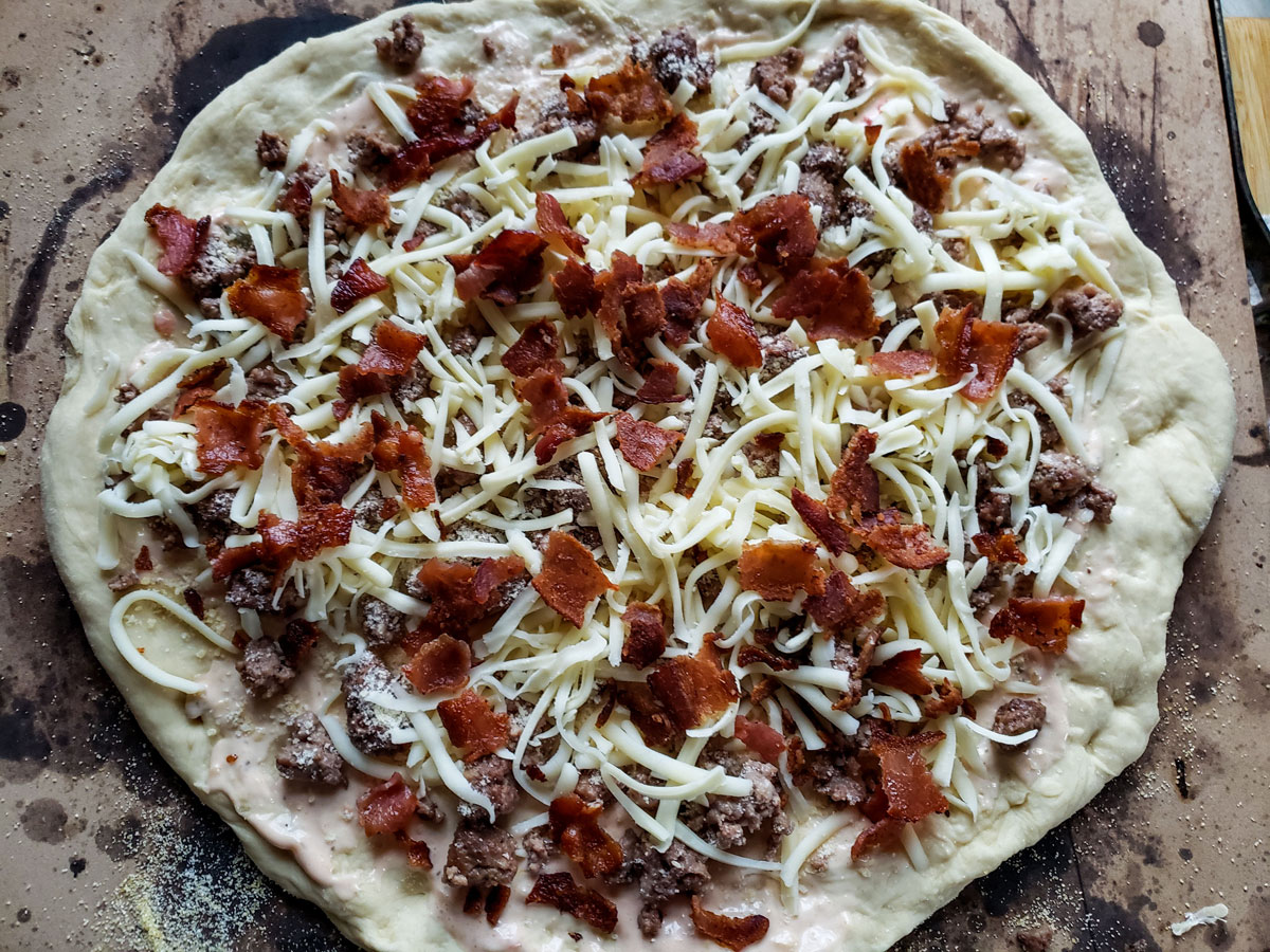 Dough topped with the bacon and the remaining cheese.