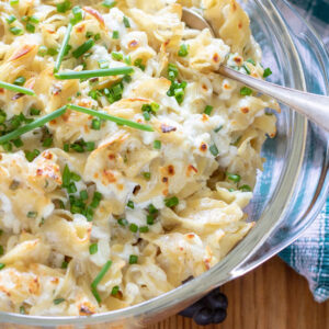 Casserole Marie Blanche in a clear casserole dish. Noodles with a creamy cottage cheese and sour cream sauce topped with snipped chives.