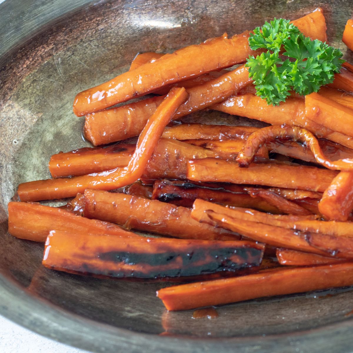 Caramelized carrots in a pewtere serving bowl.