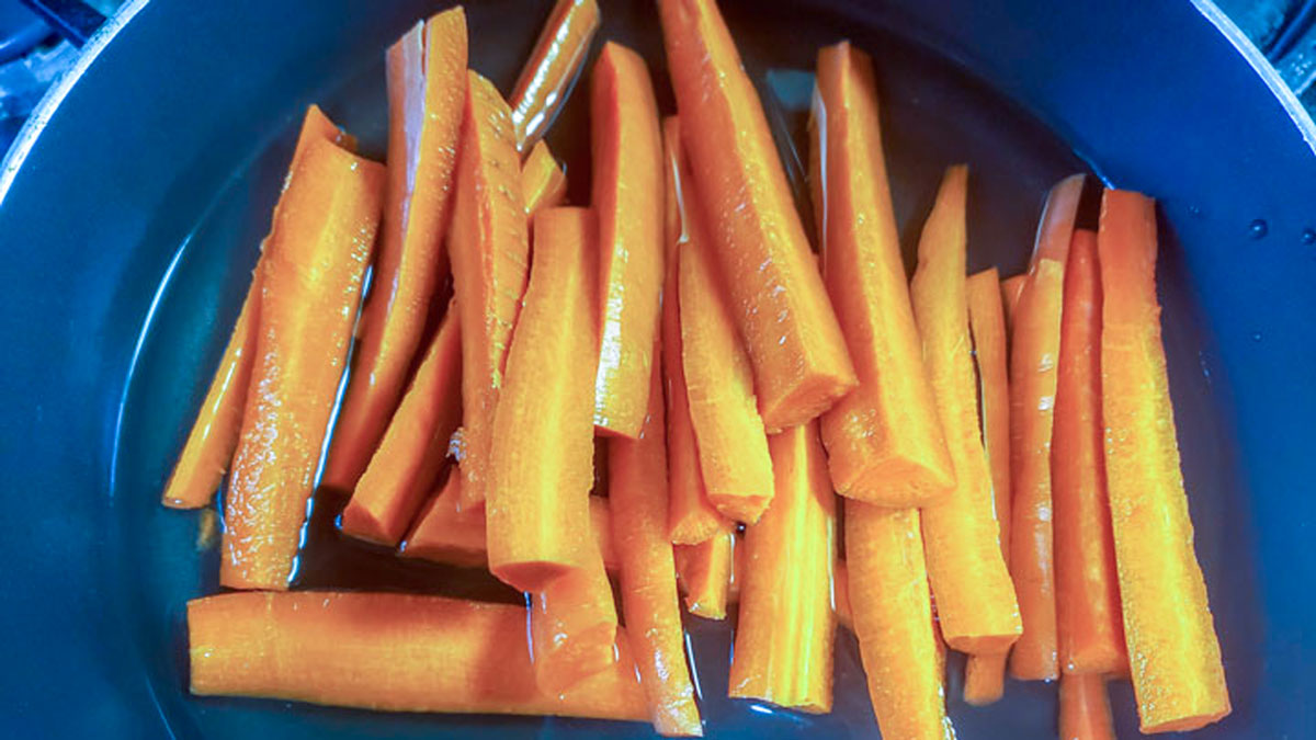 Water and carrots added to a pan.