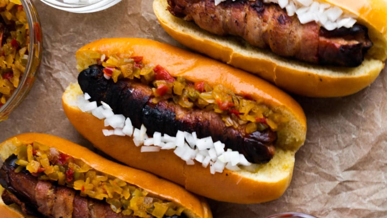 Bacon wrapped hot dogs with onions and pickles.