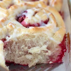 Extreme close up of cut raspberry cinnamon roll showing the fluffy texture of the roll.