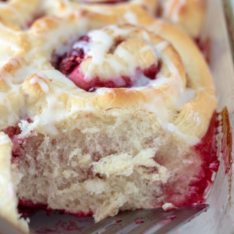 Extreme close up of cut raspberry cinnamon roll showing the fluffy texture of the roll.