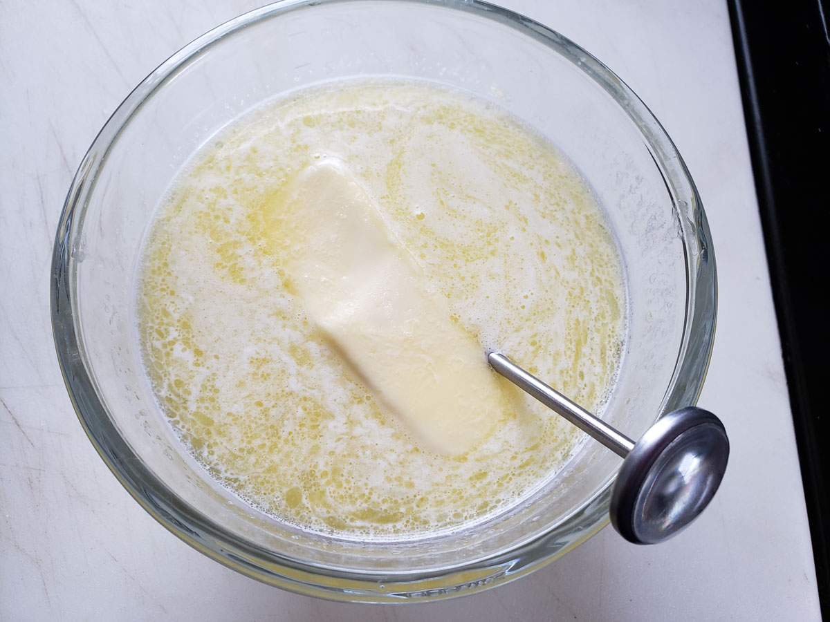 Melted butter in the bowl with a thermometer.