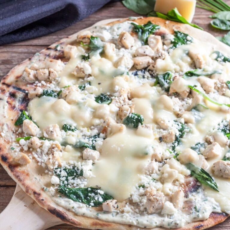 Thin Crust Chicken Pizza with Feta & Spinach on a wooden pizza peel