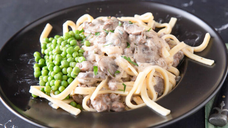 Close up of creamy stroganoff in a black bowl.