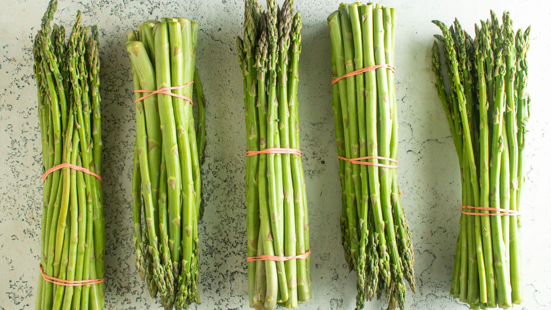Bundles of fresh asparagus on a white background.