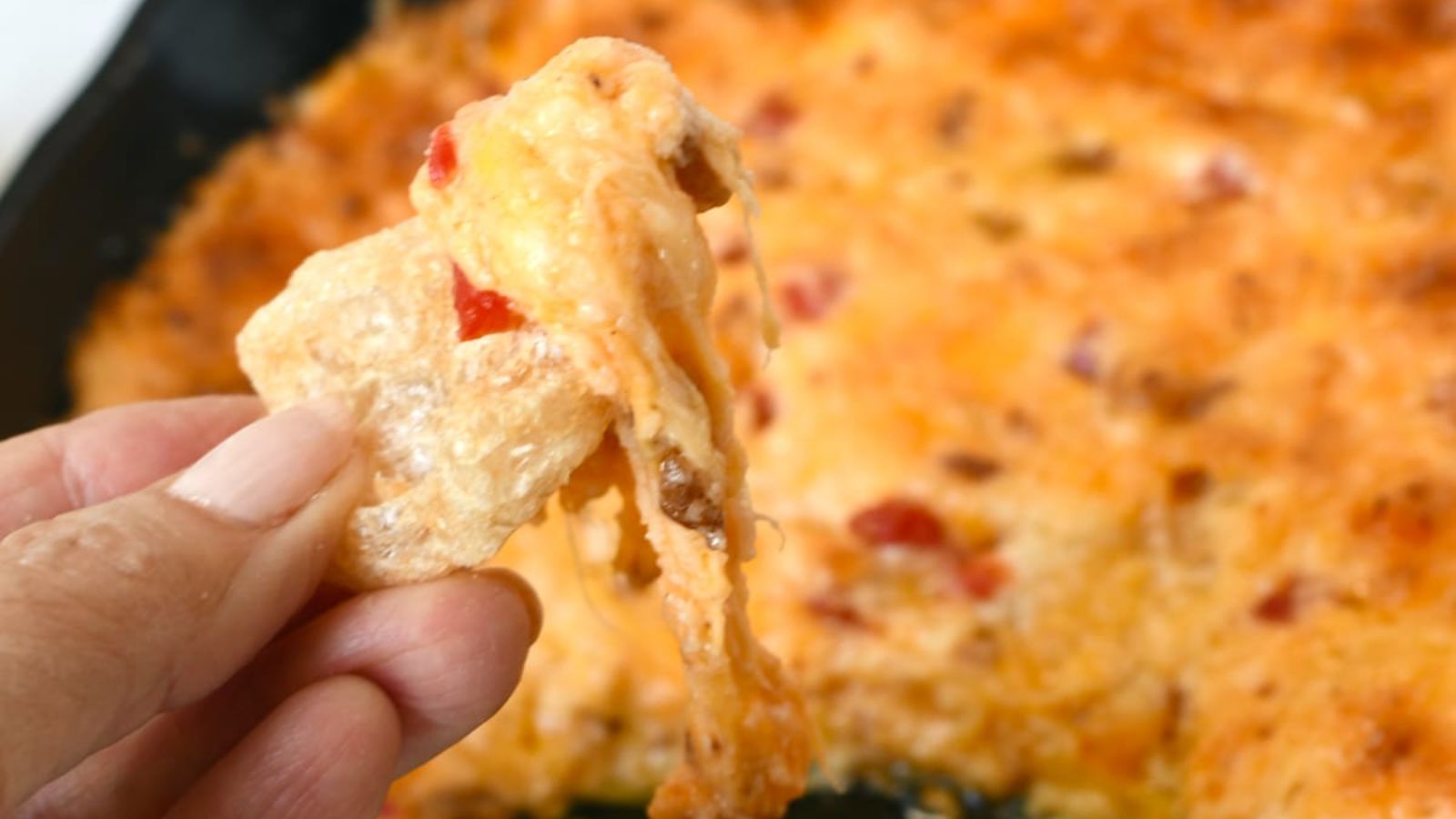 A chip dipped in to a cheese pimiento.