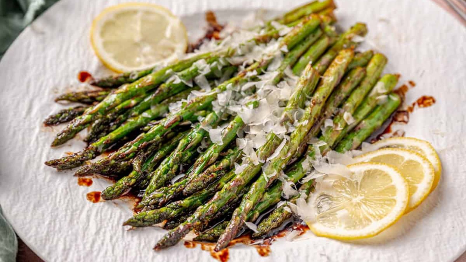 Asparagus with parmesan on top and lemons on the sides.