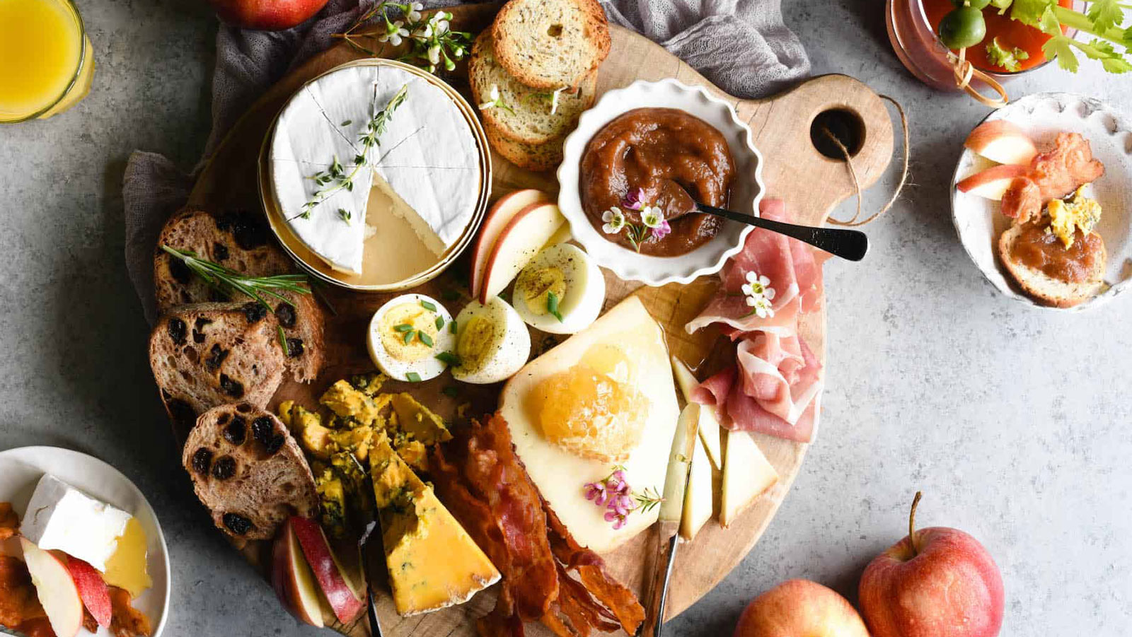 Cutting board with breakfast meats, eggs, and cheese.