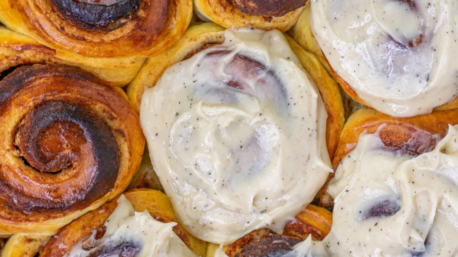 Cinnamon rolls with frosting and without in a baking sheet.