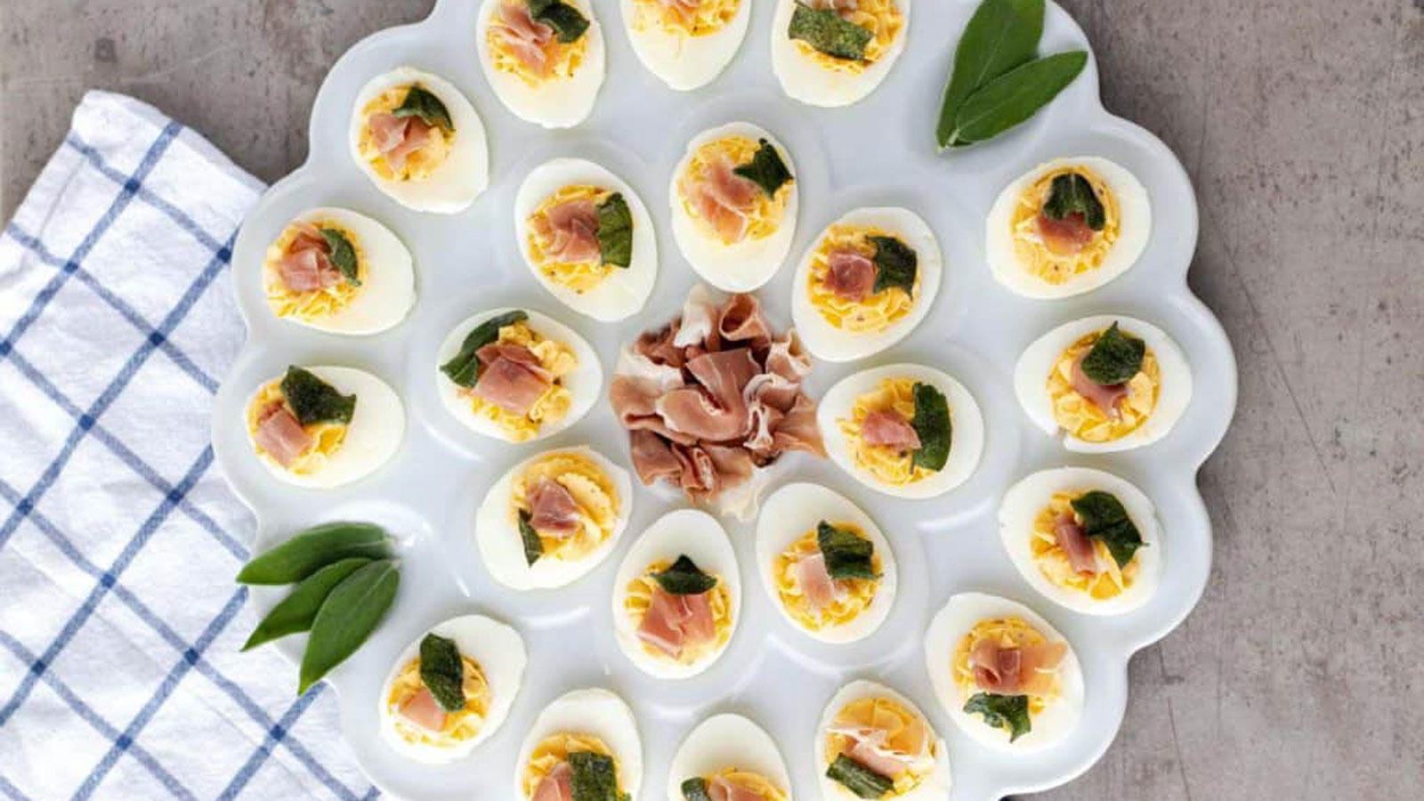 Deviled Egg platter with eggs halves garnished with sage leaves.