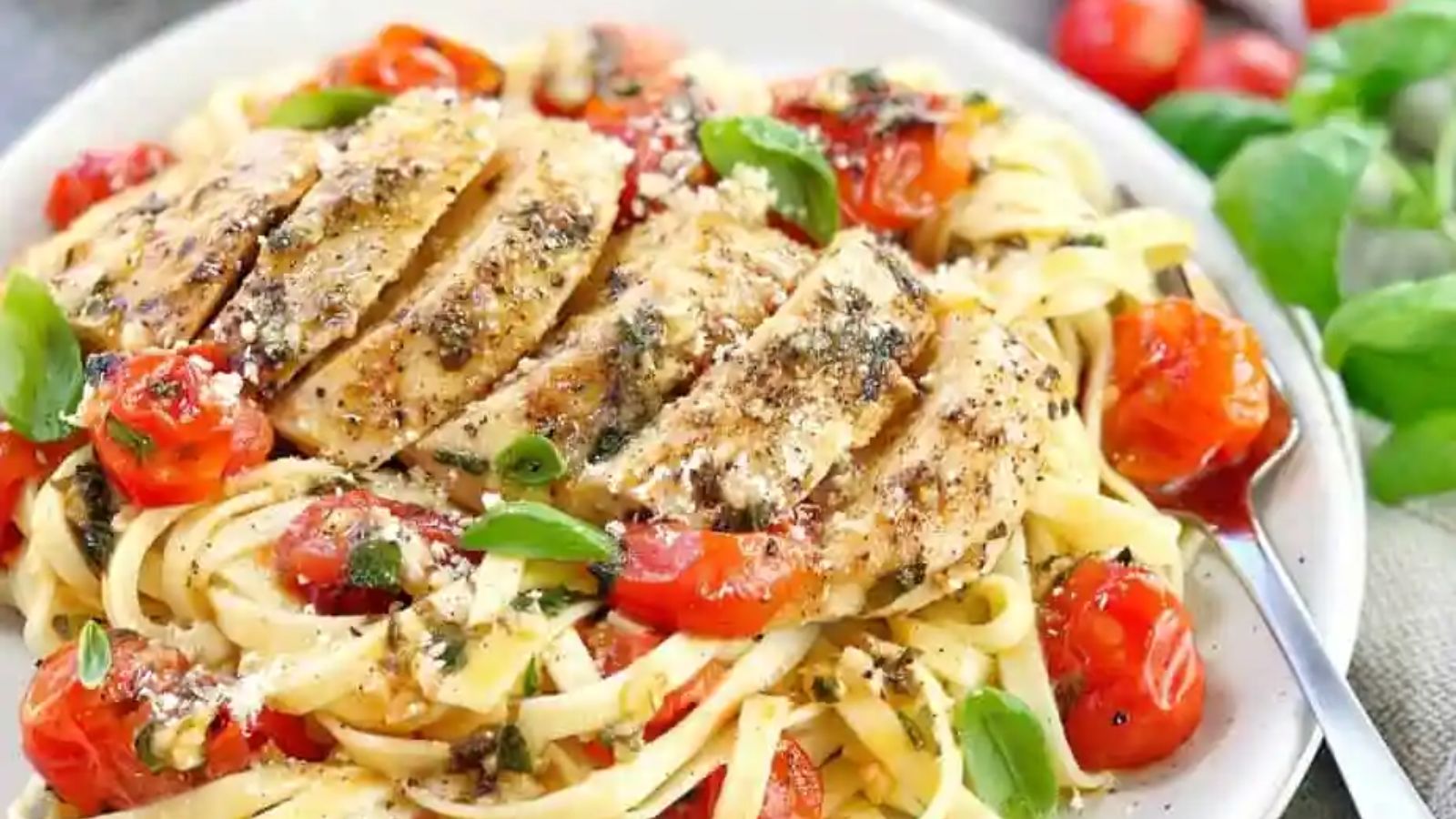 Tomato pasta with chicken on top.