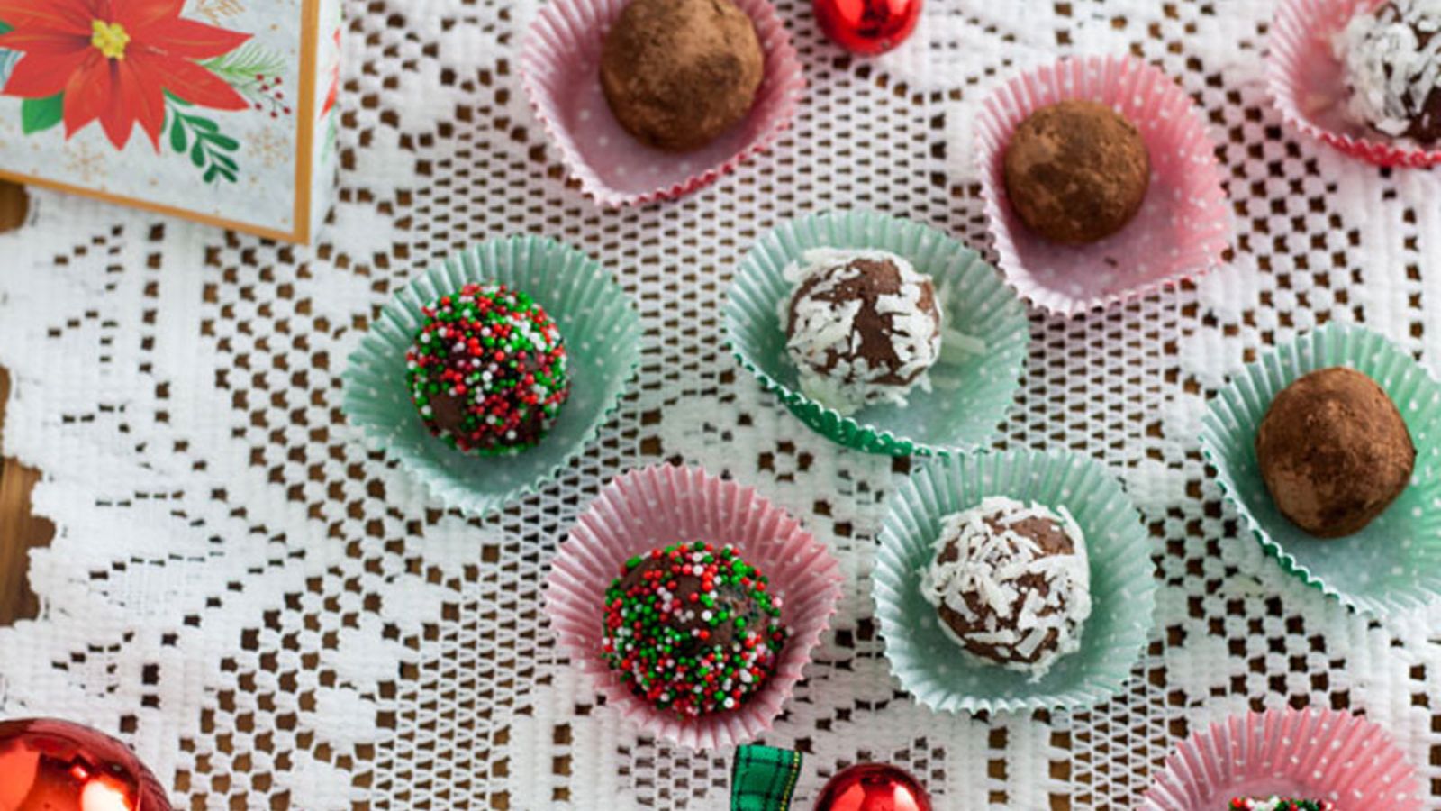 Mini chocolate truffles in red and green decorative mini cups with Christmas decorations.