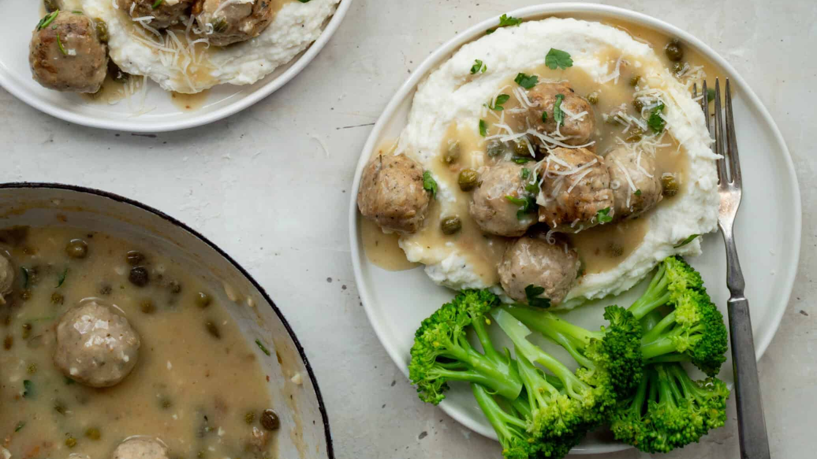 Chicken piccata meatballs on a plate with veggies on the side.