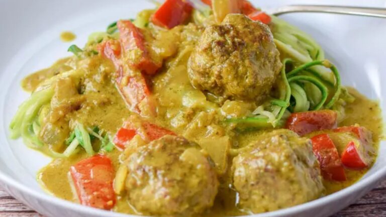 Curried meatballs with vegetables on top of zoodles.