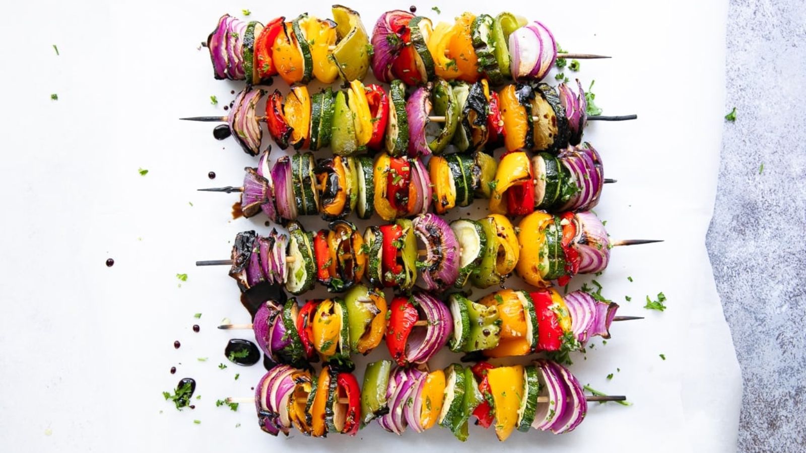 Grilled veggie skewers on a white background.