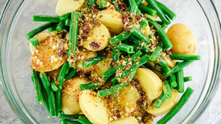 Potato salad with green beans in a glass serving bowl.