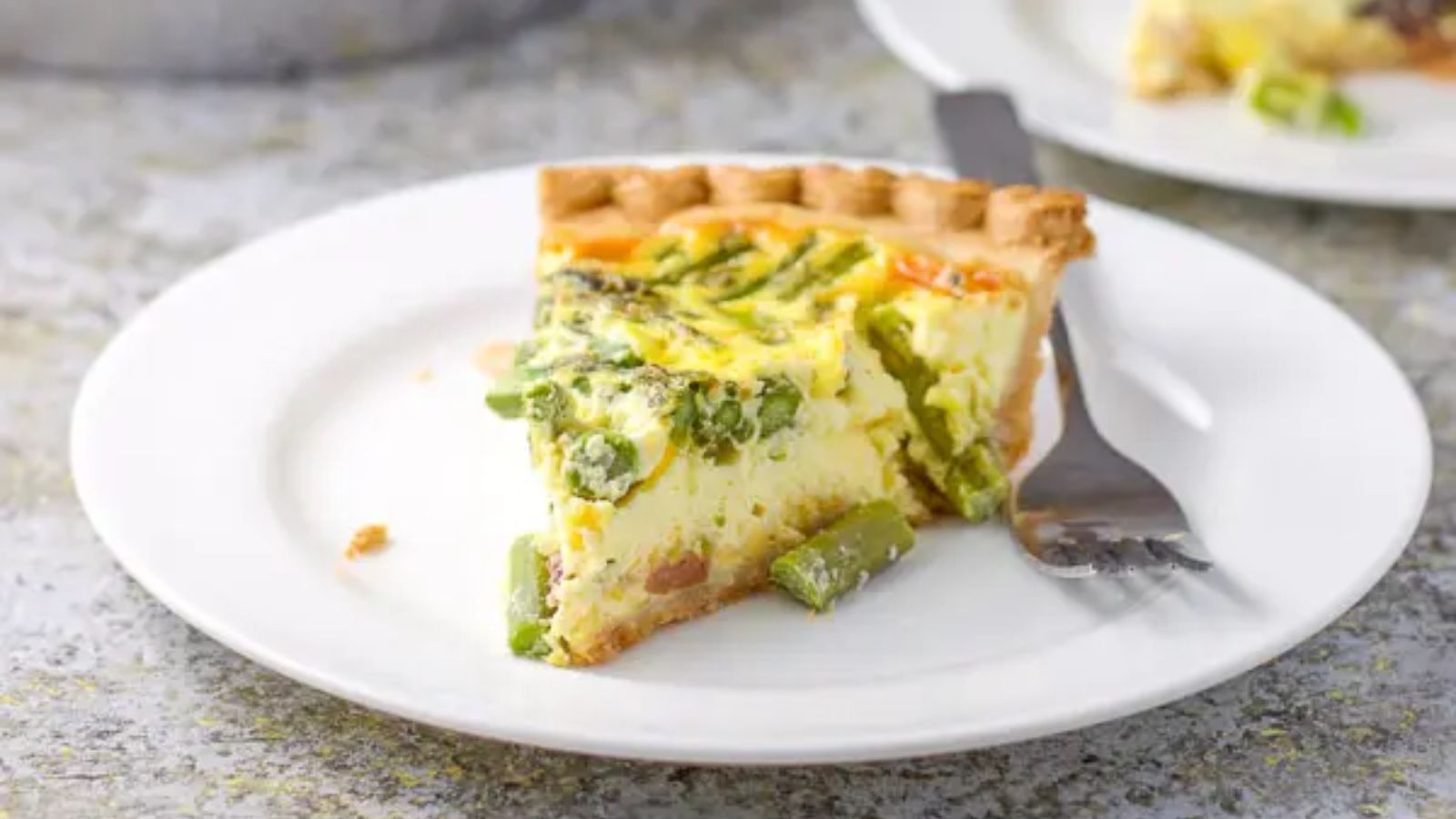Ham and asparagus quiche slice on a plate.