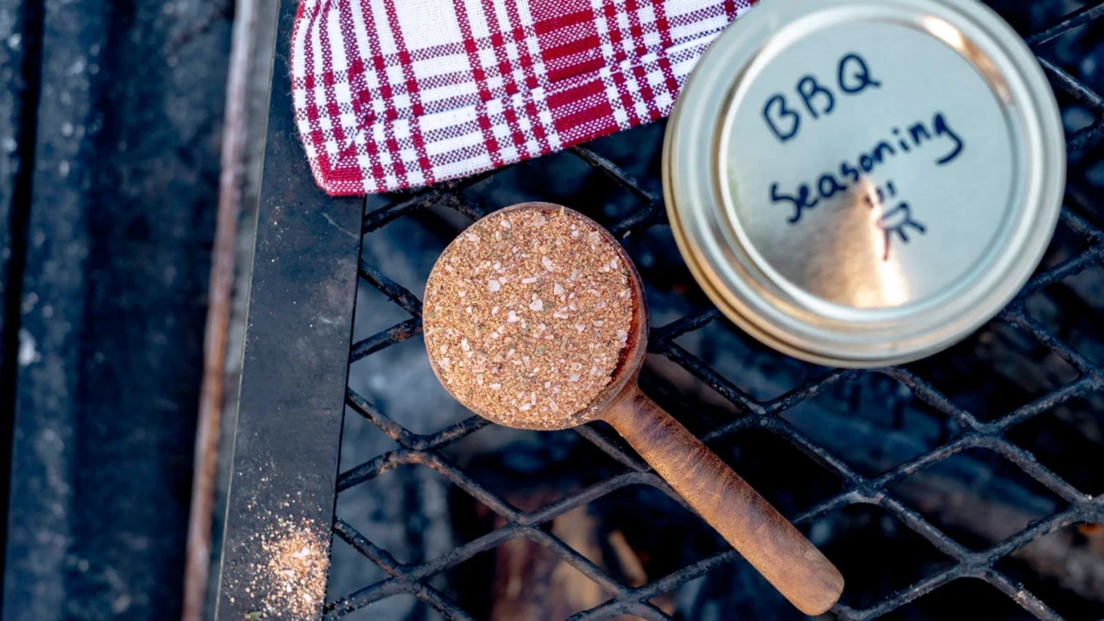 A scoop of seasoning with jar on the side.