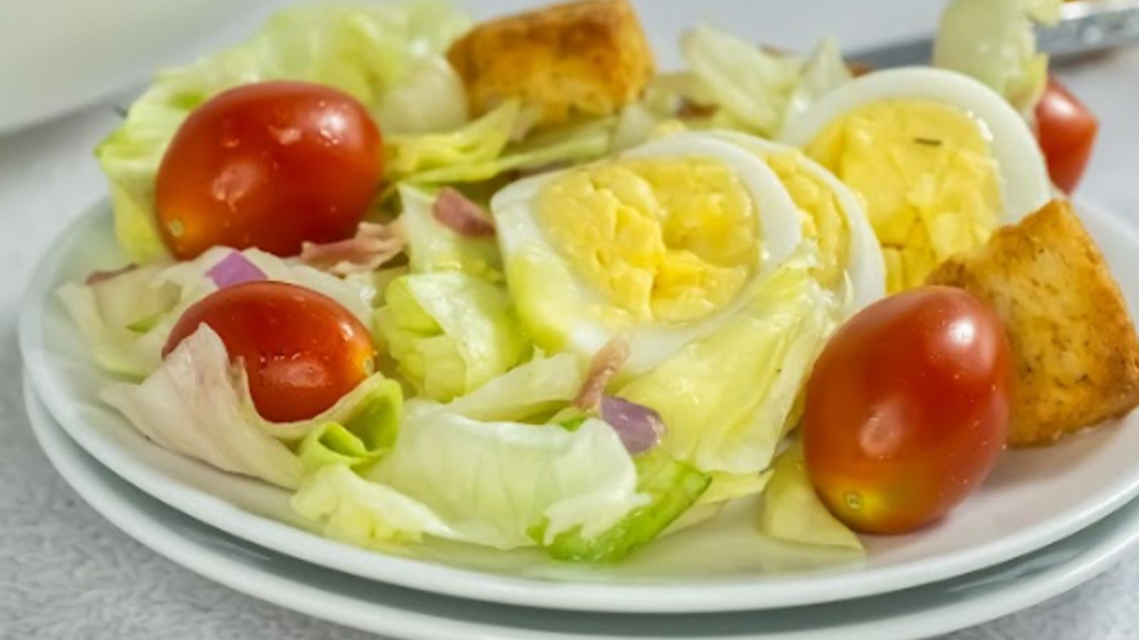 Salad on a plate with sliced eggs on top.