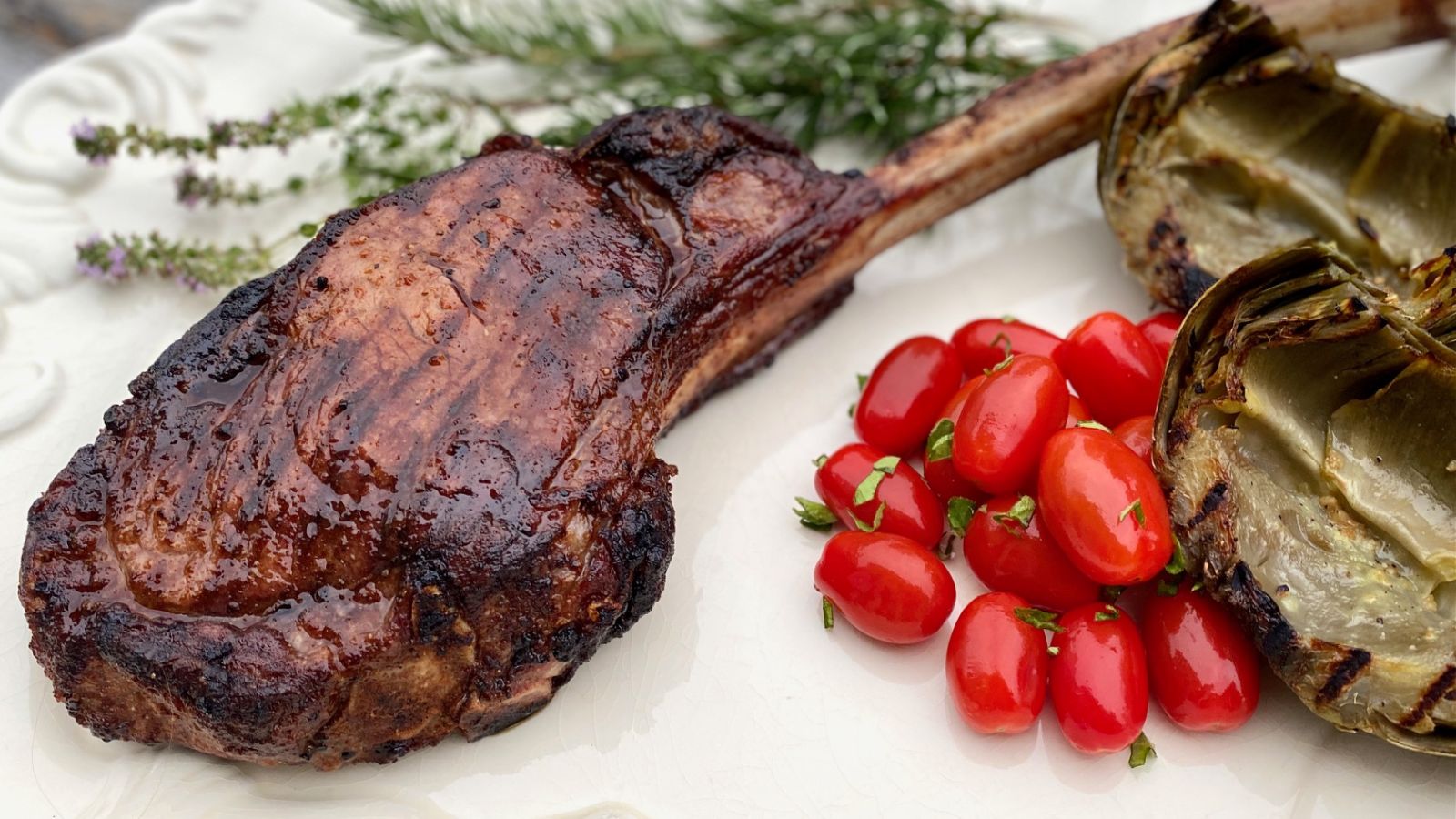 Tomahawk steak on a white plate.