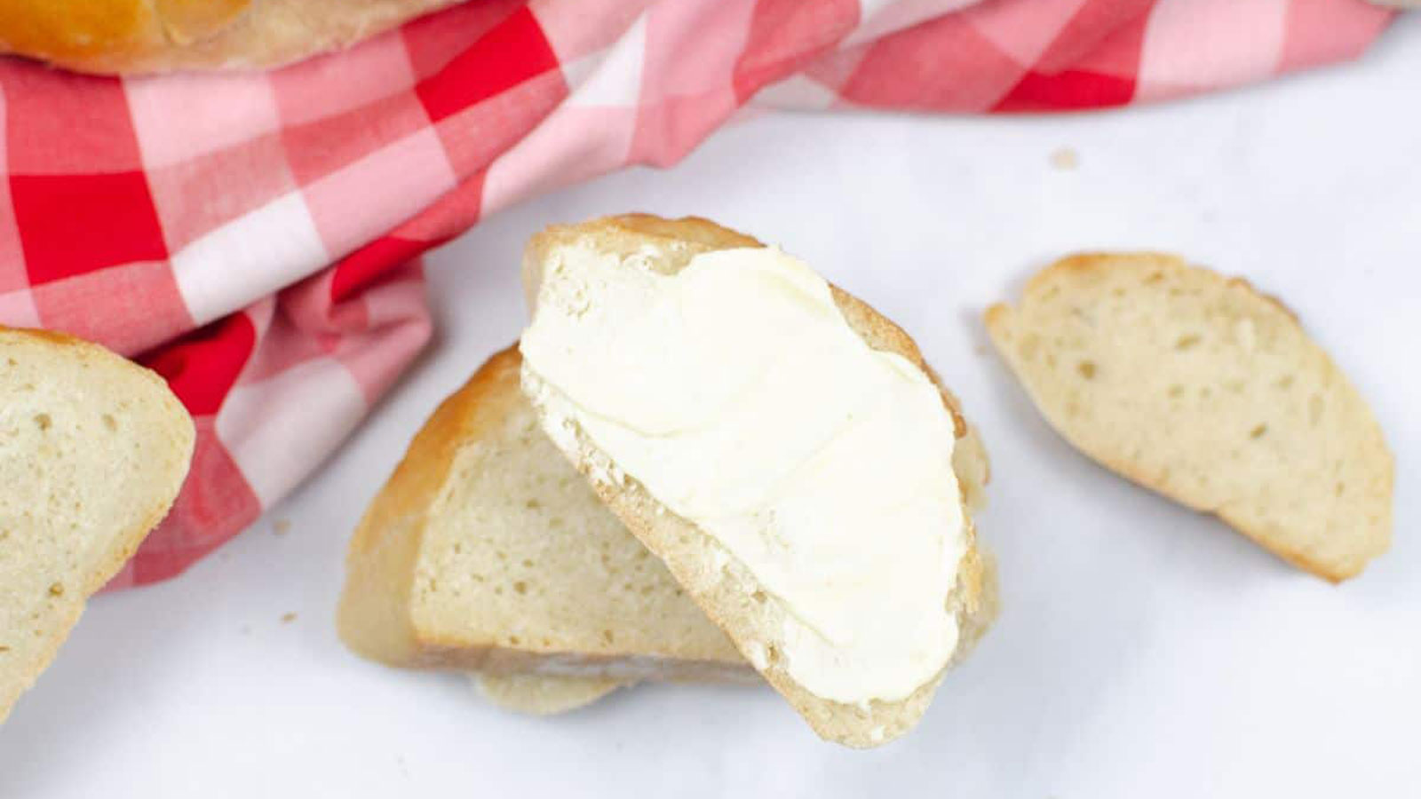 Sliced white bread with red checkerboard towel.