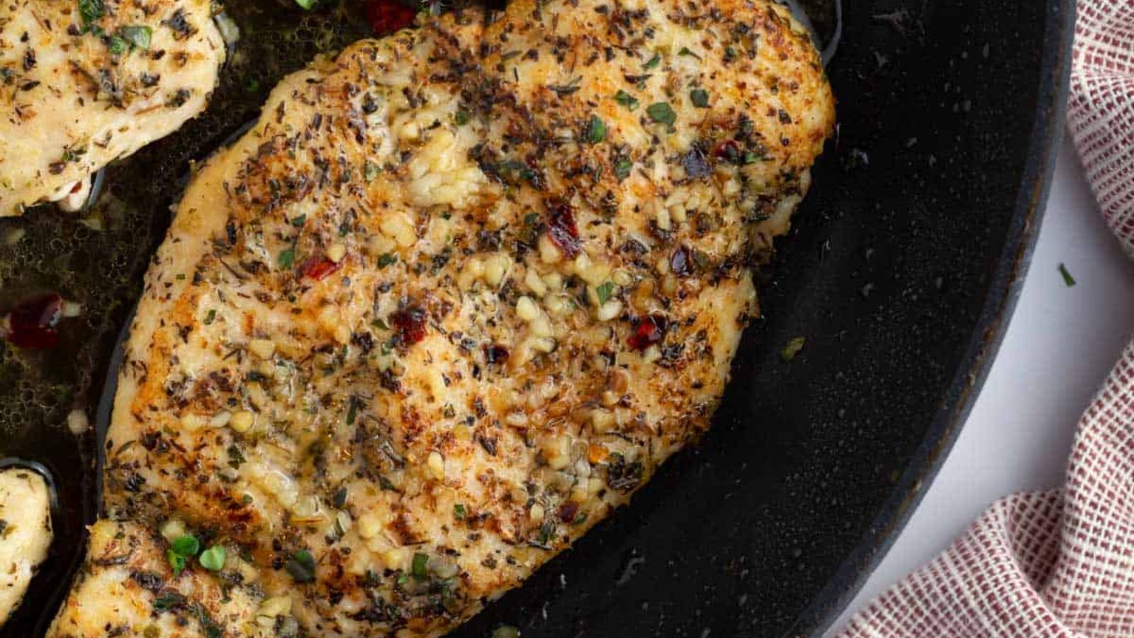 Chicken breast with spices on a pan.