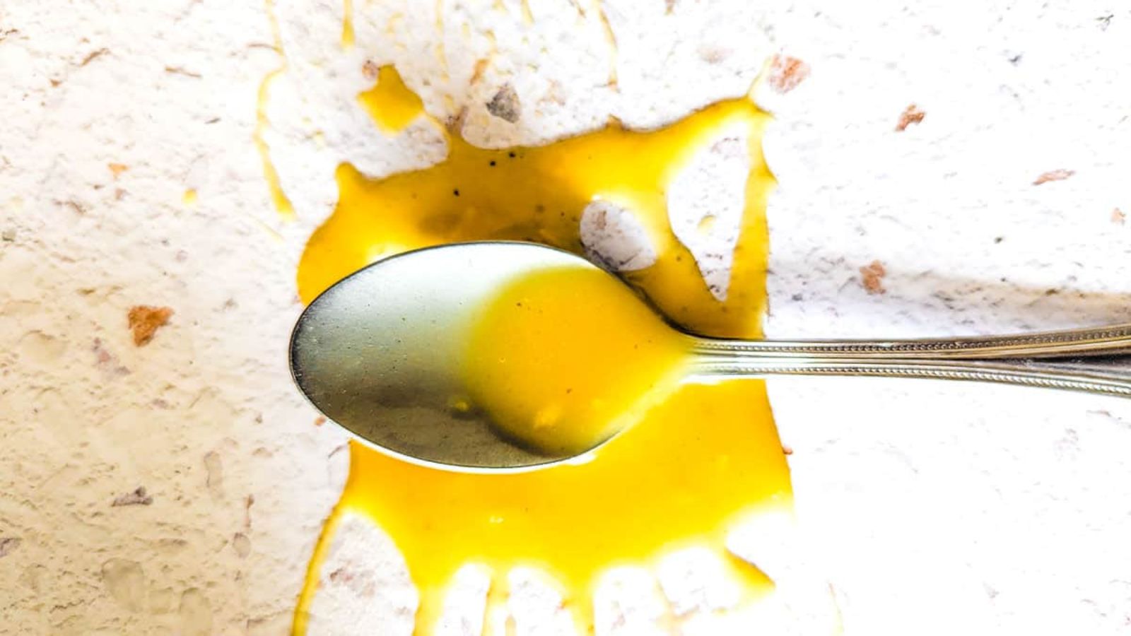 Splashed dressing on a white board with a spoon.