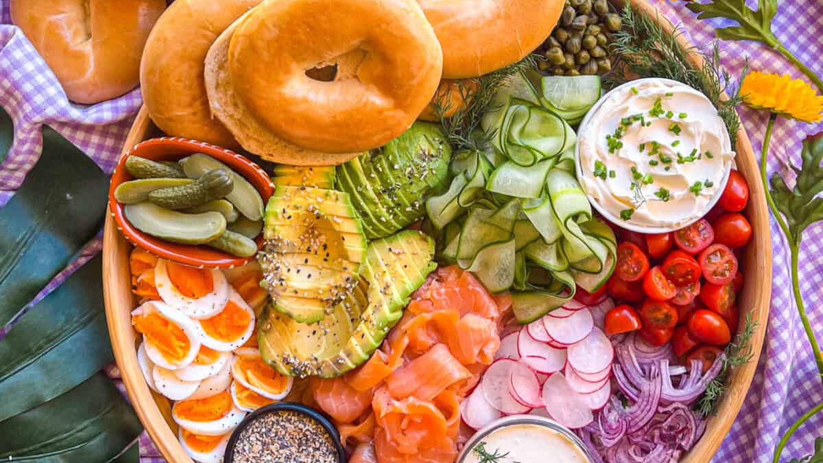 Lox, bagels, cucumber, onions and more on a round serving dish.