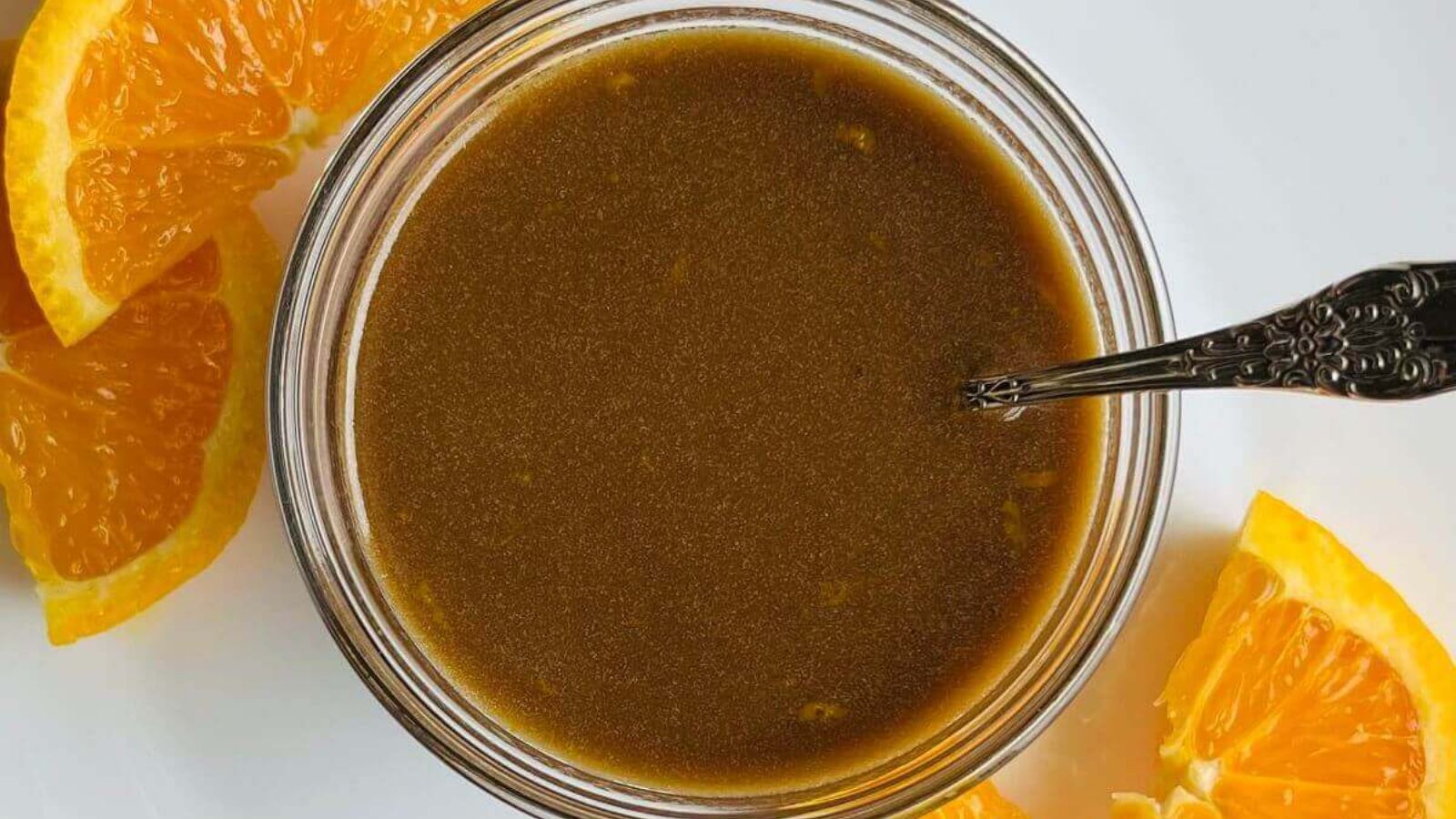 Balsamic dressing in a jar with sliced oranges on the sides.