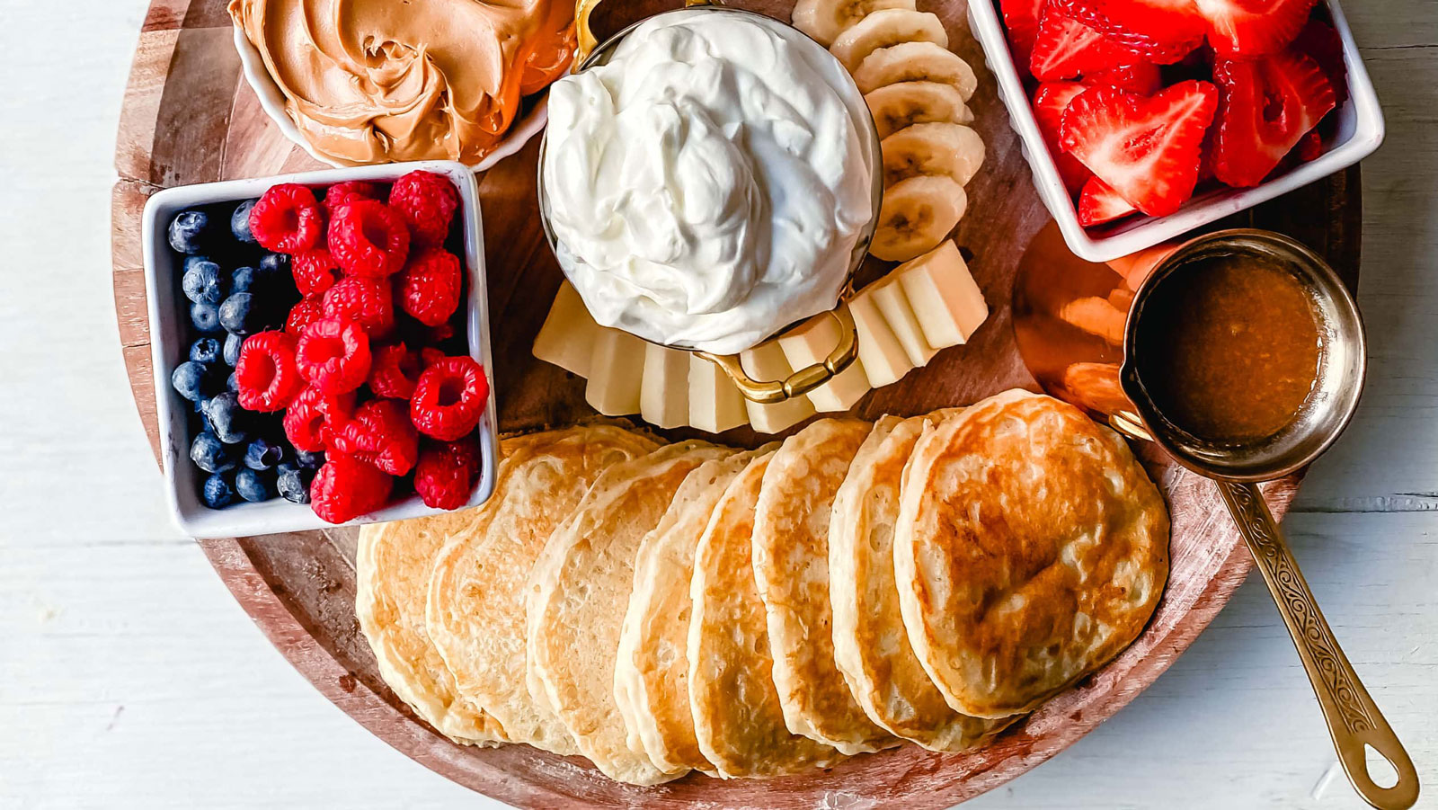 Pancakes on a platter with fruit and toppings