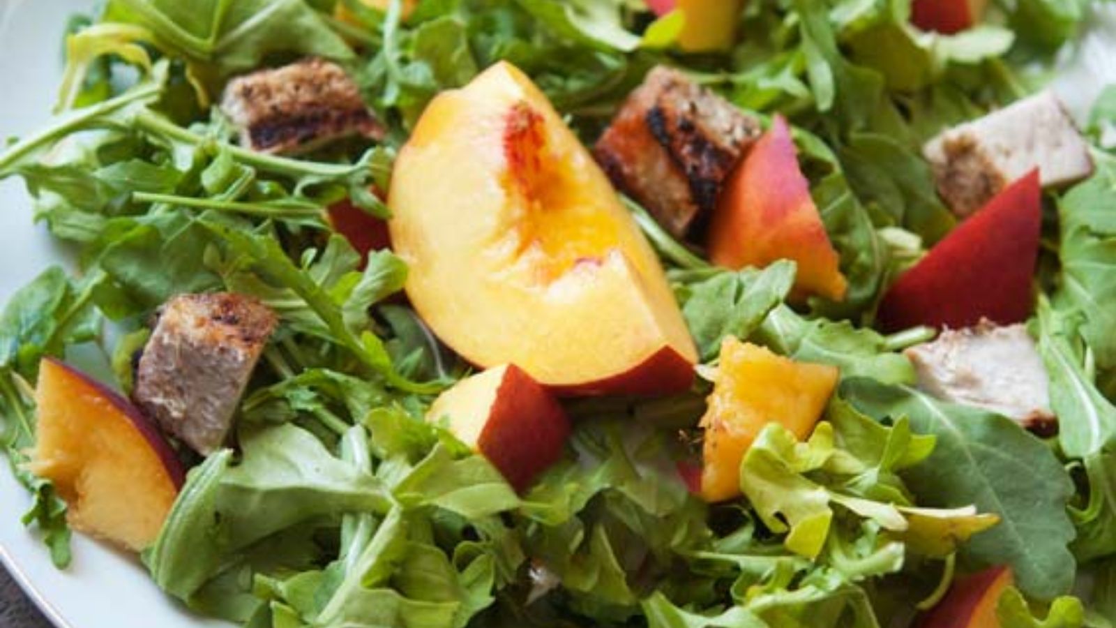 Arugula salad with peach on top.