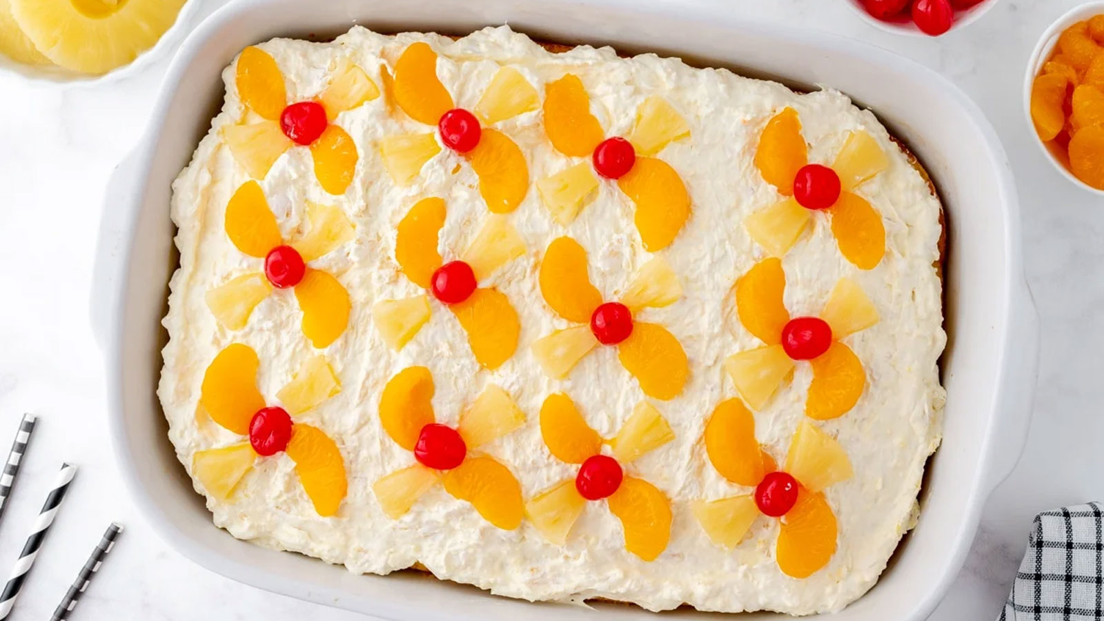 Whole cake with white icing a=garnished with cherries and oranges.