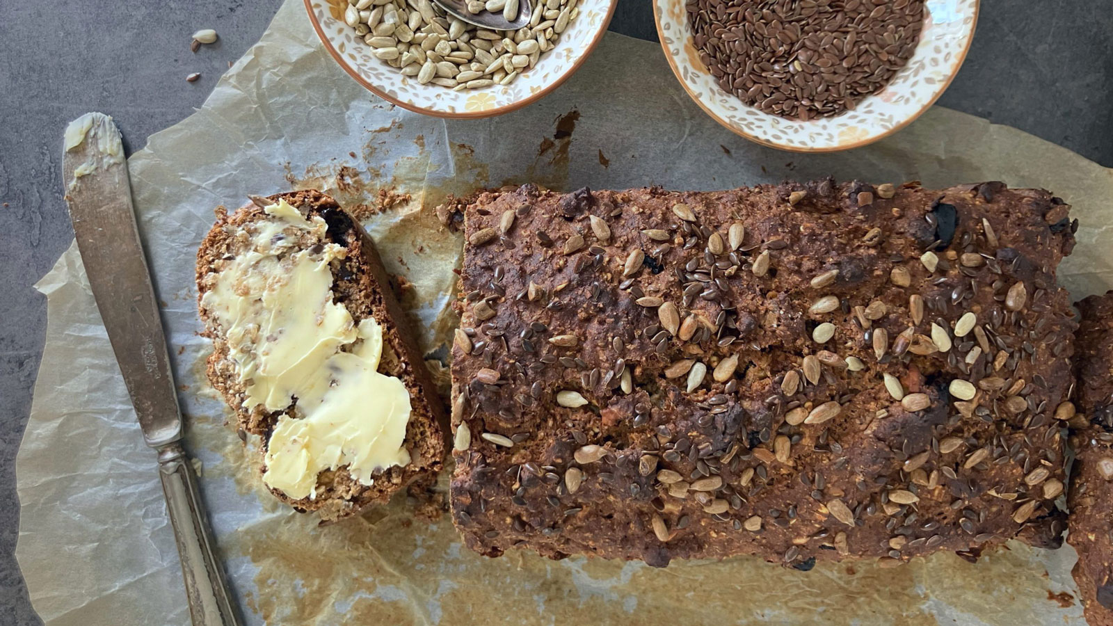 Dark Seeded rye bread with slice slathered with butter.