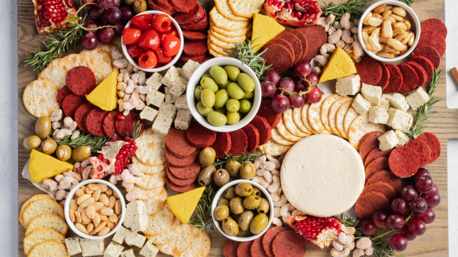 Vegan meat and cheese on a board with olives and crackers.