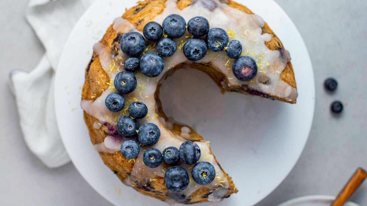 Overhead photo of a bundt cake drizzled with glaze and topped with blueberries.