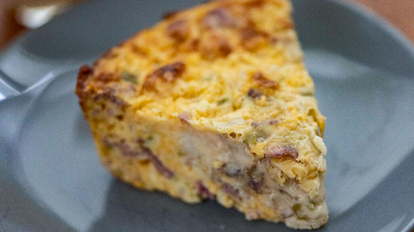 Slice of egg casserole on a gray plate.