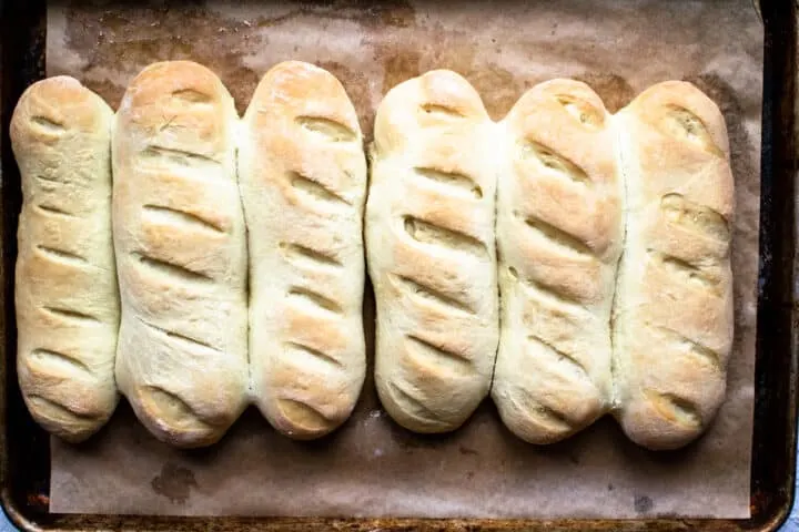 Hoagie rolls on a baking sheet.