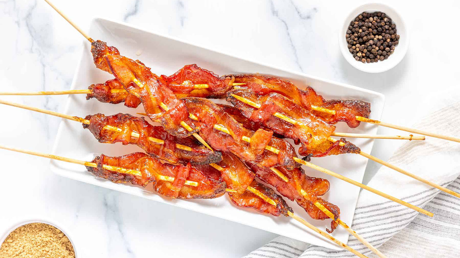 Bacon on skewers on a white plate.