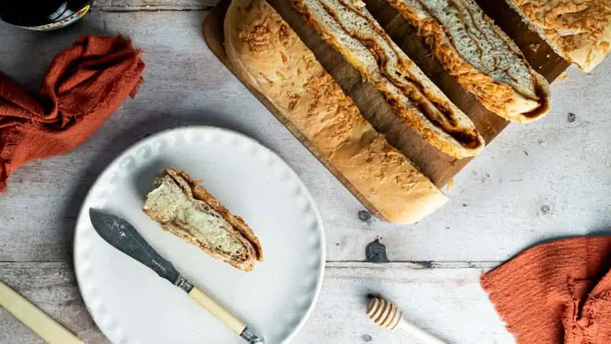 Sliced cheese and marmite bread on a white plate.