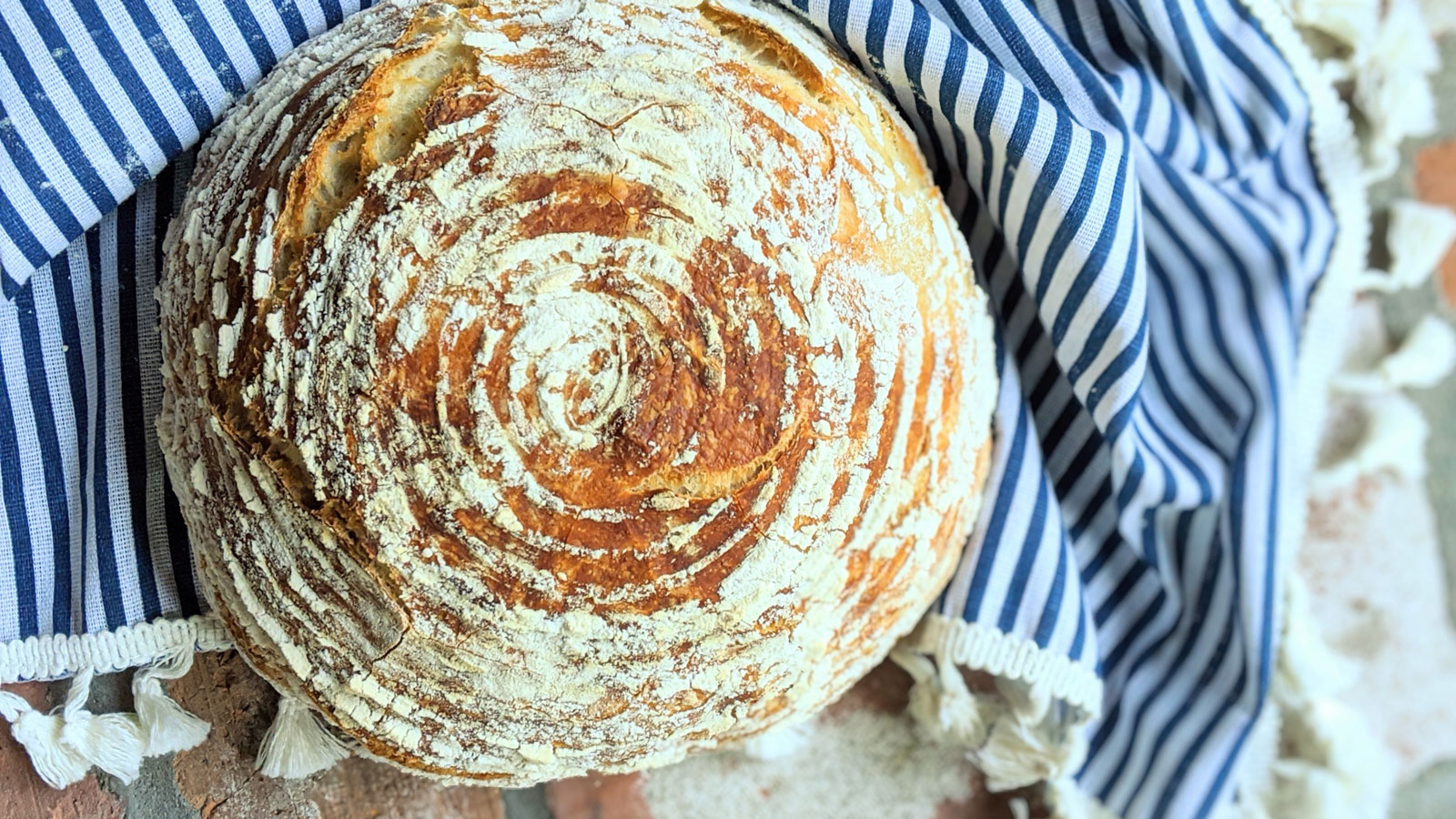 Beautiful round loaf with blue and white striped towel.