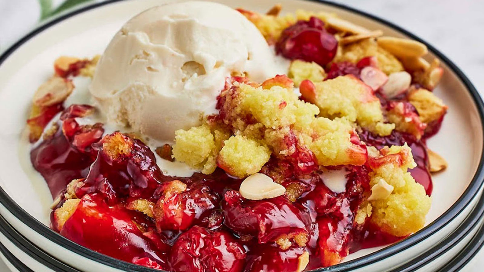 Serving of cherry dump cake on a white plate topped with ice cream.