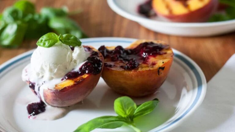 Ice cream topped grilled peaches with blackberry sauce.