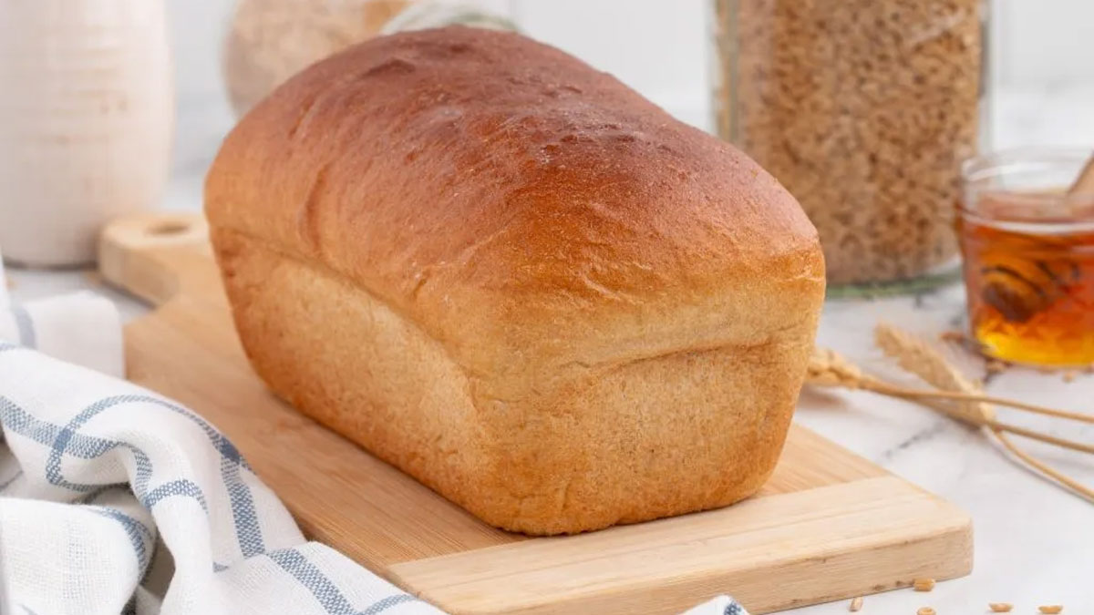 Whole loaf of wheat bread on a cutting board.